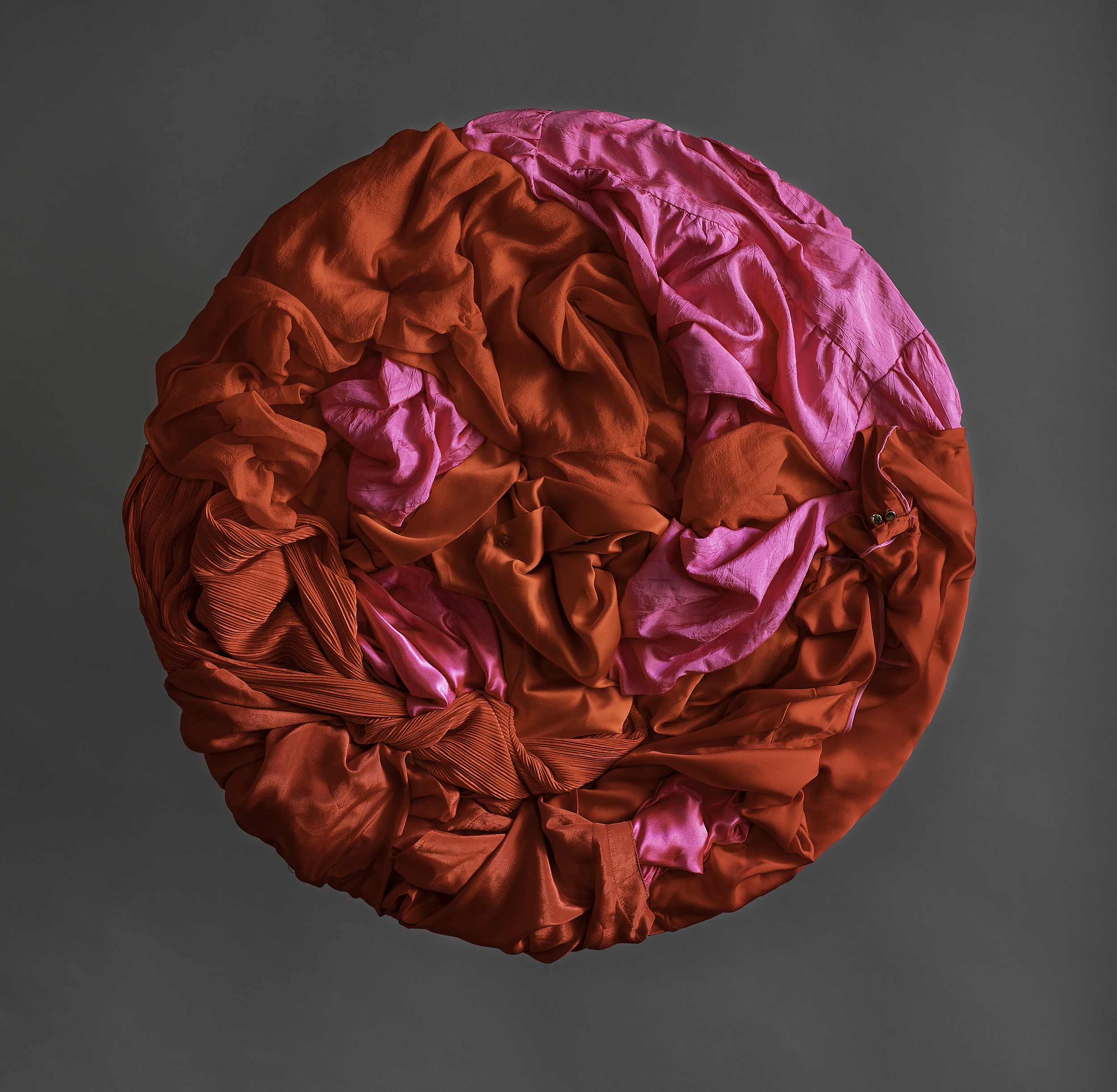 Pyöreä, punainen tekstiilitaideteos, tehty kierrätetyistä vaatteista. Taiteilijan nimi: Virpi Vesanen-Laukkanen
