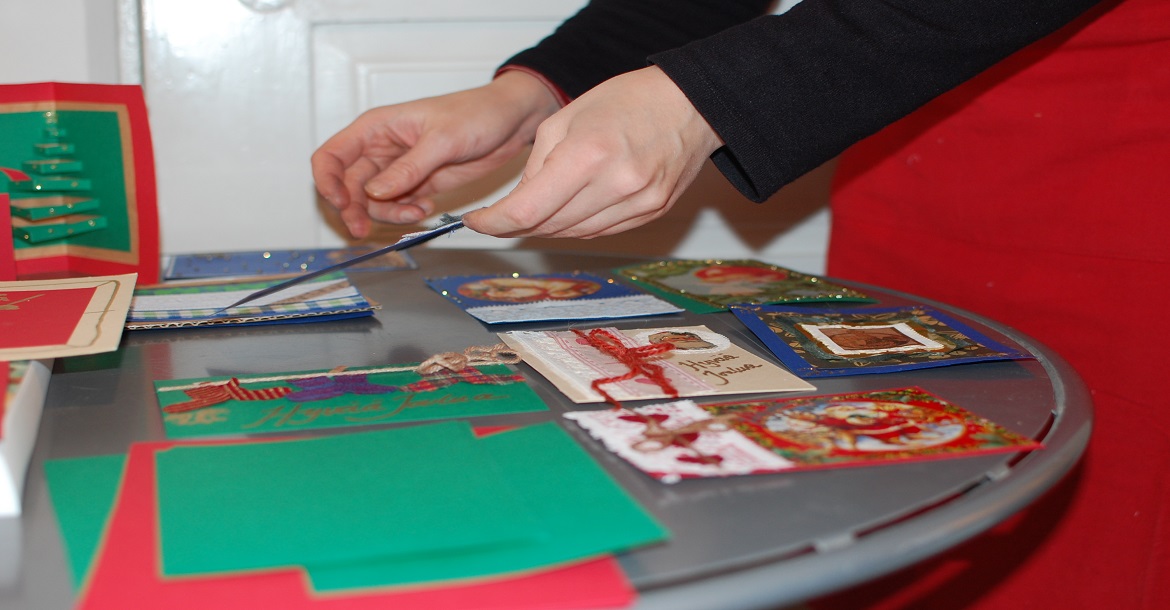 Pöytätasolle asetellaan esille erinäköisiä joulukortteja.