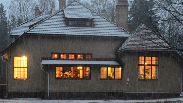 Villa Elfvikin luontotalon valot loistavat hämärässä talvi-illassa.